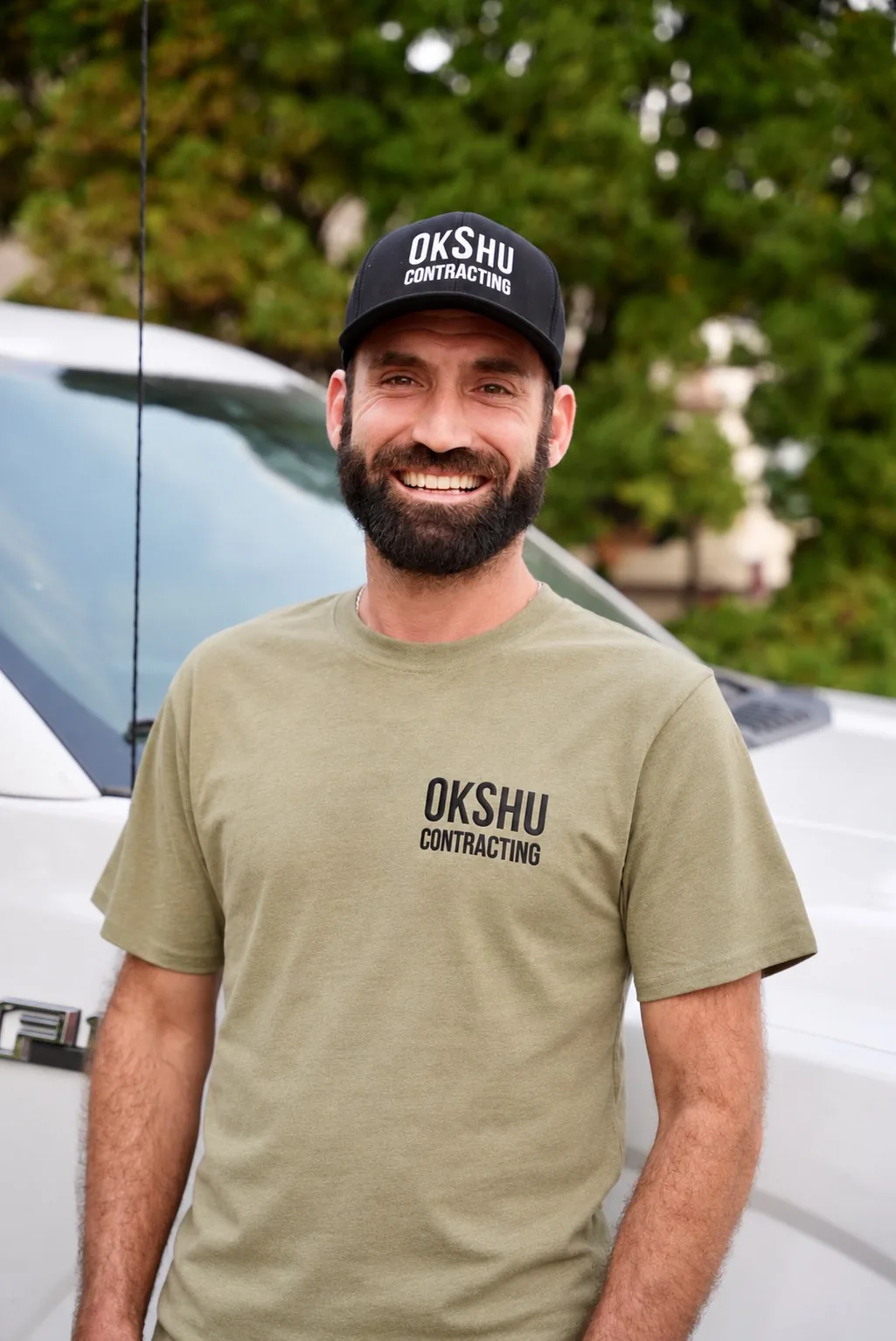 Rylan, owner of OkShu Contracting, in front of his work truck