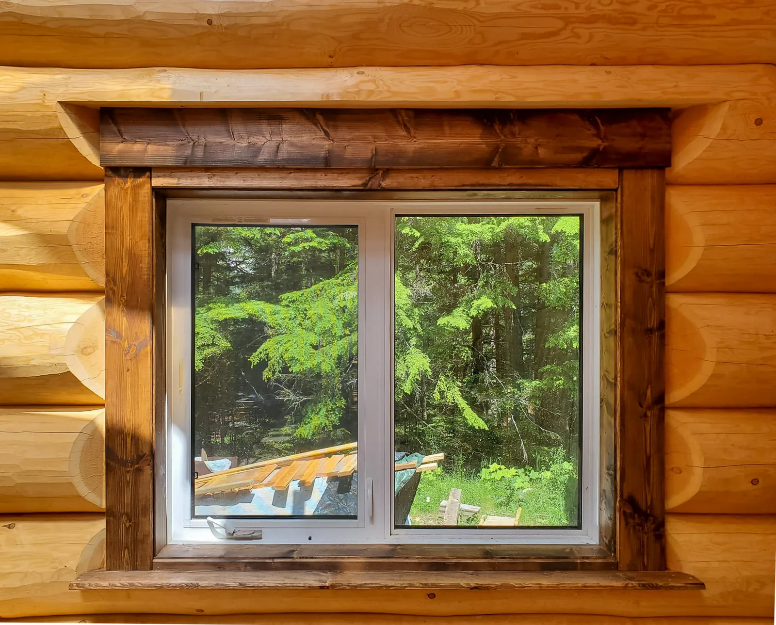 New window set into a log wall with stained timber trim