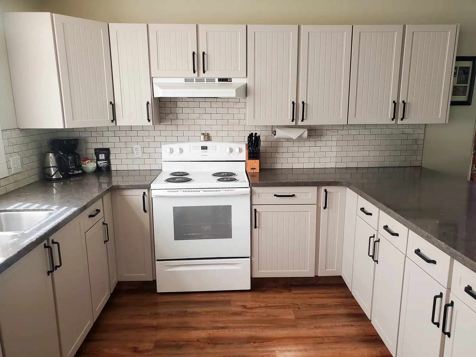 Custom range hood and granite counters in a finished kitchen